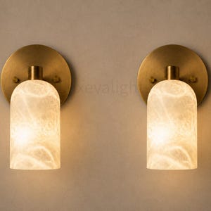Pair of modern natural alabaster wall sconces in solid antique brass, luxury mid century wall lights for bathroom vanity, bedroom bedside, hallway and living room
Modern antique brass alabaster wall sconce pair with warm lighting for luxury bathroom vanity and bedroom decor
Handmade solid antique brass wall sconces with natural alabaster shades, modern mid century wall lighting
Luxury natural alabaster wall light pair in antique brass finish for bathroom vanity, bedside and hallway lighting