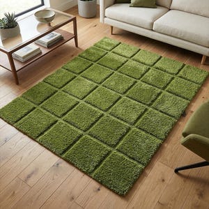 May include: A green shag rug with a geometric, square pattern. The rug is a vibrant shade of green and has a plush, textured surface. The rug is placed on a wooden floor, and is near a sofa and a chair.