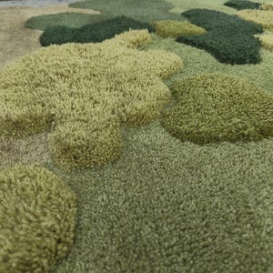 May include: A close-up view of a green and tan rug with a textured, tufted design. The rug features various shades of green and tan, with raised, cloud-like shapes. The design creates a soft, plush appearance, suitable for home decor.
