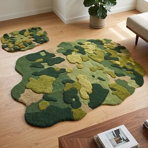 May include: A large, irregularly shaped rug and a smaller matching mat. The rugs feature a camouflage-like pattern in shades of green, tan, and olive. The textured surface adds depth and visual interest, suitable for a living room or bedroom.