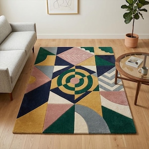 Puede incluir: Una alfombra geométrica multicolor con una variedad de formas y colores, incluyendo azul marino, amarillo, rosa, verde y blanco. La alfombra presenta un diseño circular central y un patrón de hojas. La alfombra está colocada sobre un suelo de madera.