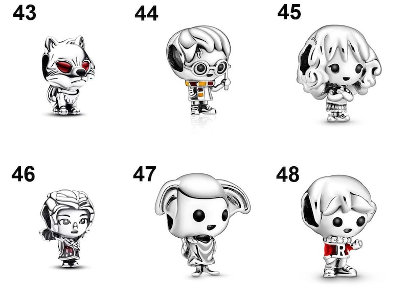 May include: A collection of six silver-toned metal charms labeled 43 through 48. The charms feature stylized figures including a fox with red eyes, a boy with glasses and a wand, a girl with curly hair, a figure with wings, an elf, and a boy in a sweater.