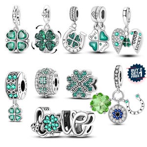 May include: A collection of silver charms with green and clear accents. Charms include four-leaf clovers, a horseshoe, and the word "LOVE". Some charms have the text "Best Friends" and "Good Lucky".
