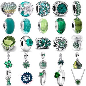 May include: A collection of silver charms and jewelry with green and teal accents. Charms include beads, pendants, and rings with various designs, such as hearts, flowers, and clovers. Some charms are adorned with sparkling crystals, while others feature unique textures and shapes.