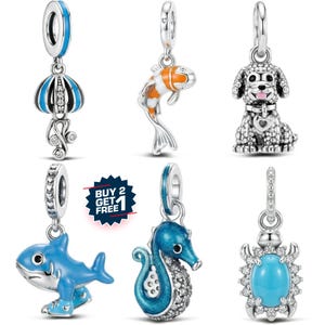 May include: A collection of silver charms with various designs. Includes a blue and white jellyfish, an orange and white fish, a dog with a heart collar, a blue shark, a blue seahorse, and a turquoise stone.