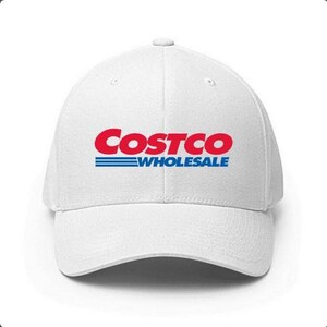 May include: White baseball cap with the Costco Wholesale logo in red and blue. The logo is centered on the front of the cap. The cap has a curved brim and a structured fit.