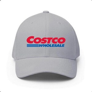 May include: A light gray baseball cap featuring the Costco Wholesale logo in red and blue. The logo is prominently displayed on the front of the cap. The cap has a curved brim and a structured fit.