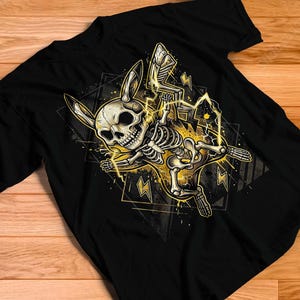 Puede incluir: Una camiseta negra de manga corta con un estampado gráfico de un esqueleto de criatura estilizada con orejas largas. El esqueleto está rodeado de rayos amarillos brillantes y formas geométricas, creando un diseño de alto contraste.