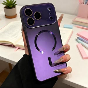 May include: A purple and black phone case with a gradient design. The case has a large circular cutout and a smaller, vertical cutout. The case has a glossy finish and is designed to fit a phone with multiple camera lenses.