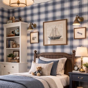 Puede incluir: Un dormitorio acogedor con una cama de madera, papel pintado a cuadros azul y blanco y un edredón azul. Un osito de peluche está sentado en las almohadas. La habitación incluye una mesita de noche, una estantería y un otomán tejido. Una obra de arte enmarcada de un velero cuelga en la pared.