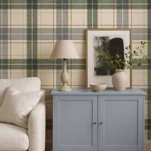Puede incluir: Interior de salón con un aparador azul, una lámpara y obras de arte enmarcadas. El fondo presenta un papel pintado a cuadros en tonos verdes, beige y marrones. A la izquierda se ve un sofá blanco. El aparador mide unos 100 cm de ancho.