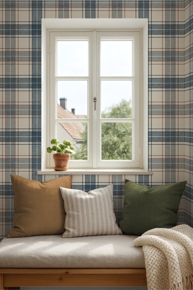 Puede incluir: Un banco de ventana con tres cojines en tonos marr&oacute;n, blanco y verde. Una manta de punto crema est&aacute; colocada en el asiento. El marco blanco de la ventana y las paredes est&aacute;n cubiertos con papel pintado a cuadros azul y blanco. Una planta est&aacute; en el alf&eacute;izar.