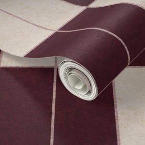 May include: A roll of wallpaper featuring a grid pattern with alternating dark burgundy and off-white squares. The surface has a subtle, textured appearance, and the paper is partially unrolled to reveal the inner white core of the roll.