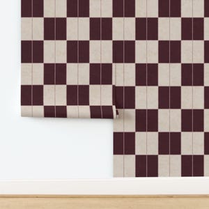 May include: A roll of wallpaper featuring a repeating checkerboard pattern of dark maroon and off-white rectangular blocks. The design includes thin, vertical lines running through the center of each block, creating a structured grid effect.