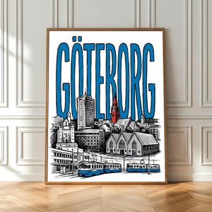 Op de afbeelding: Een ingelijste kunstdruk met een zwart-witte schets van een stadsgezicht, met het woord "GÖTEBORG" in grote blauwe letters. Het kunstwerk toont gebouwen, trams en een kerk met een rood dak. De lijst is bruin.