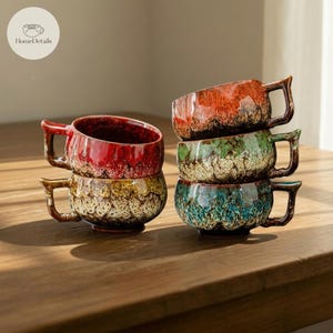 Może przedstawiać: Stos czterech ceramicznych kubków z unikalnym, nakrapianym szkliwem. Kubki są w odcieniach czerwieni, zieleni i niebieskiego, z brązowymi uchwytami. Kubki są ułożone na drewnianej powierzchni. Logo HomeDetails znajduje się w lewym górnym rogu.