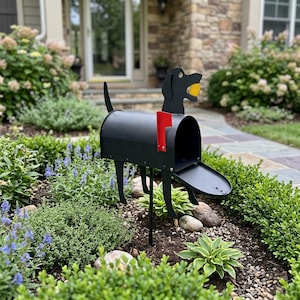 Peut inclure: Une boîte aux lettres en métal noir en forme de chien avec une balle jaune dans la gueule et un drapeau rouge sur le côté. La boîte aux lettres est soutenue par quatre fines pattes en métal et possède une porte avant articulée qui s'ouvre.
