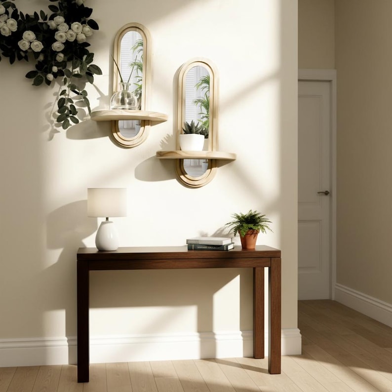 May include: Two arched wall mirrors with attached shelves, each holding a small plant. A dark brown console table with a white lamp and a potted plant sits below. A white door is visible in the background.