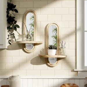 May include: Two wooden wall mirrors with shelves. Each mirror has an arched top and a small shelf below. One shelf holds a clear vase with a plant, the other holds a white pot with a succulent and a glass jar.
