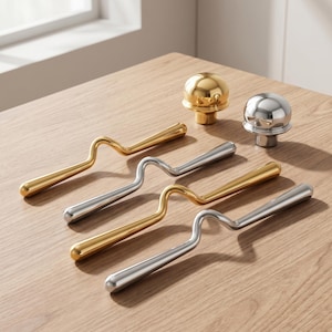 May include: A collection of metal hardware including two spherical knobs in polished gold and silver finishes, alongside four elongated, wavy-shaped handles in alternating gold and silver tones, all featuring a smooth, reflective metallic surface.