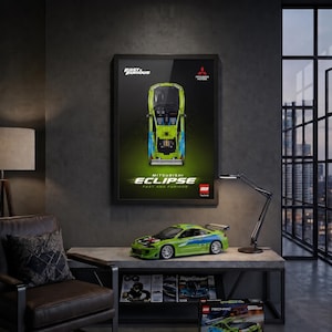 May include: A lime green and blue LEGO Technic Mitsubishi Eclipse model car from Fast & Furious, displayed on a table with a matching framed poster above it. The poster features a top-down view of the car with the text Fast & Furious and Eclipse.