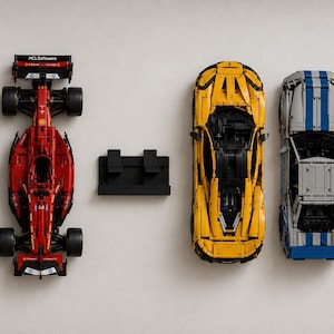 Puede incluir: Una colección de cinco vehículos de juguete y un soporte de plástico negro dispuestos en fila. El conjunto incluye un coche deportivo azul oscuro con rayas blancas, un coche de carreras de Fórmula 1 rojo, un superdeportivo amarillo, un coche gris y un GT3 RS blanco.