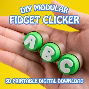 May include: Three modular fidget clickers with the letters A, B, and C. Each clicker has a green top with a white letter, a brown ring, and is held in a hand. The text "DIY MODULAR FIDGET CLICKER" and "3D PRINTABLE DIGITAL DOWNLOAD" are also visible.
