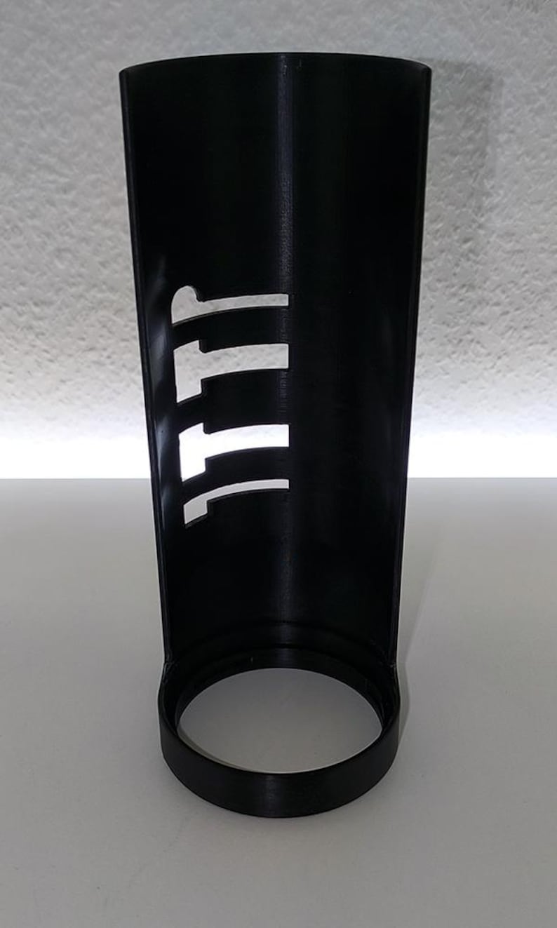 May include: A black, cylindrical container with a circular base. The side of the container has a series of white, vertical cutouts forming the letters "111". The object is made of a matte material.