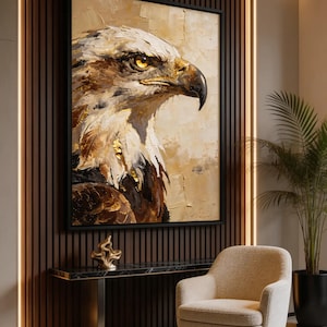 Peut inclure: Tableau d'un aigle aux tons bruns, blancs et dorés, encadré de noir. Il est suspendu au-dessus d'une console en marbre noir avec un piètement doré. Un fauteuil beige et une plante en pot complètent la décoration.