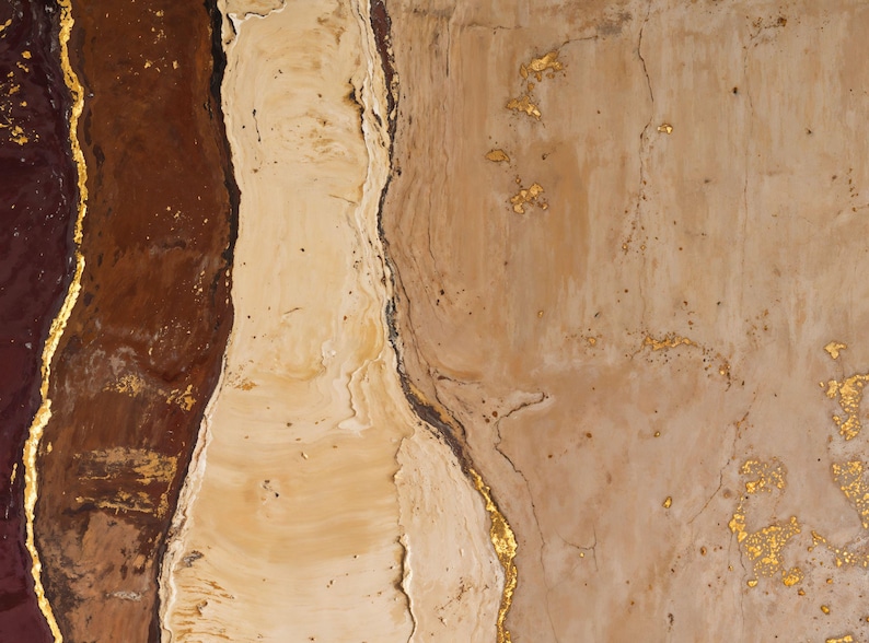 May include: An abstract painting featuring vertical bands of deep burgundy, creamy beige, and light tan. The sections are separated by thin, textured lines of metallic gold leaf, with additional gold leaf accents scattered across the surface.