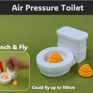 Könnte beinhalten: Ein weißes Spielzeug-WC mit der Aufschrift Air Pressure Toilet und einer Punch & Fly-Funktion. Das Set enthält zwei orangefarbene, spiralförmige Figuren. Ein Inset zeigt den Mechanismus mit einem roten Pfeil und einer Flugweite bis 100cm.