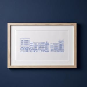 以下が含まれることがあります： 青い線画で描かれた都市のスカイラインが特徴の額入りプリント。アートワークには、建物の詳細な建築要素が含まれています。プリントは明るい木製のフレームに収められており、クリーンでモダンな美しさを生み出しています。「Covent Garden, London」の文字が見えます。