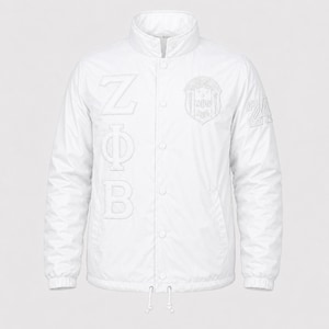 May include: A white snap-button jacket featuring a high collar and a drawstring hem. The front displays the Greek letters ZΦB vertically on the right side, a circular crest on the left chest, and the number 24 embroidered on the left sleeve.