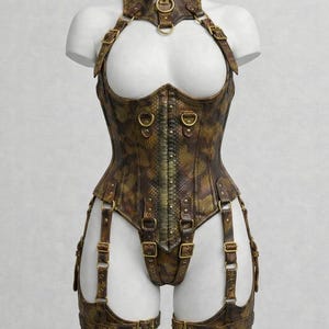 Peut inclure: Un corset marron et doré à motif peau de serpent, avec un ras du cou et des jarretières assortis. Le corset comporte des boucles et des anneaux en métal, présenté sur un buste de mannequin blanc.