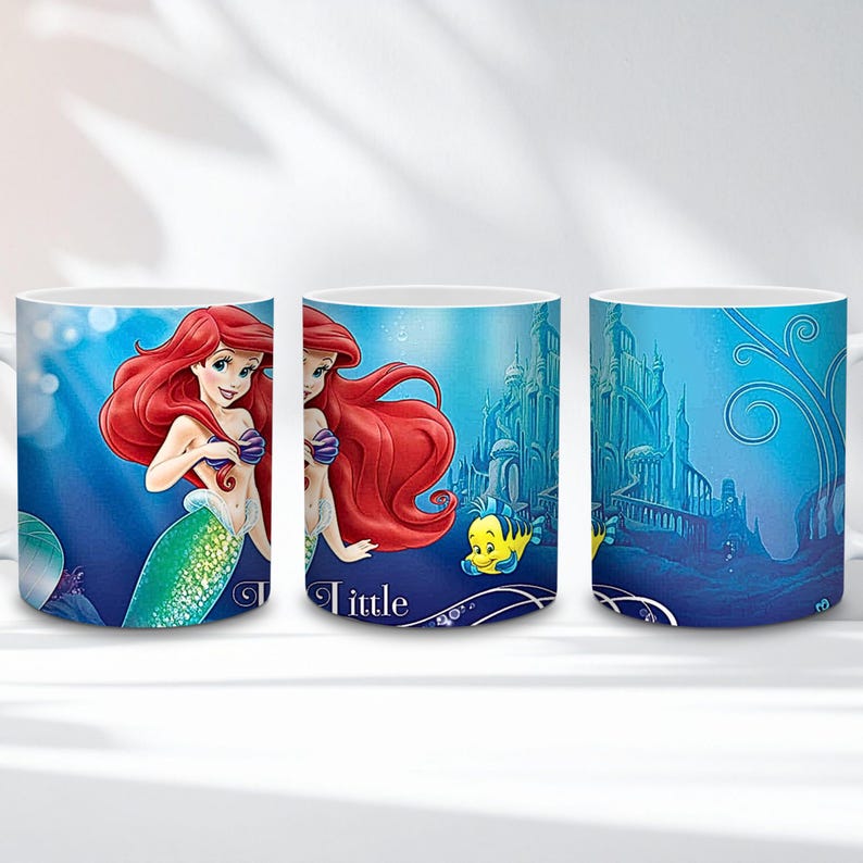 Op de afbeelding: Witte keramische mok met Ariel uit De Kleine Zeemeermin. Het ontwerp toont Ariel met rood haar en een groene staart, samen met de tekst "Little" en een gele vis. De achtergrond is een blauwe onderwater sc&egrave;ne.