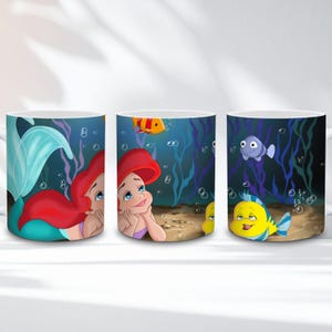 Op de afbeelding: Drie witte keramische mokken met illustraties van Ariel uit De Kleine Zeemeermin. De mokken tonen Ariel met rood haar, een blauwe staart en zeedieren zoals Botje en een paarse vis, tegen een blauwe onderwaterachtergrond.
