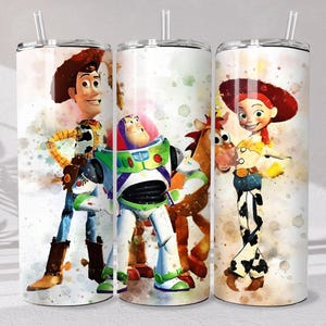 May include: Three cylindrical tumblers with clear plastic straws, each featuring a watercolor-style print of Toy Story characters including Woody, Buzz Lightyear, Bullseye, and Jessie against a white background with colorful paint splatters.