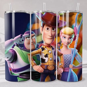 May include: A cylindrical tumbler with a clear straw featuring a wrap-around graphic of Toy Story characters including Buzz Lightyear, Woody, and Bo Peep. The design displays Buzz in a salute, Woody in his cowboy attire, and Bo Peep holding her staff.