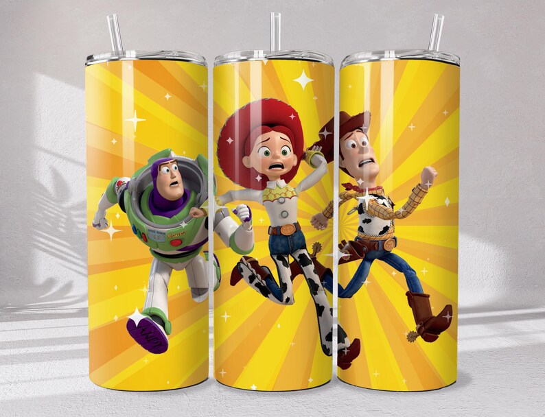 May include: A cylindrical tumbler with a straw featuring a bright yellow background with radiating sunburst lines and white sparkles. The design displays three animated characters in motion, including a space ranger and two cow-themed figures.