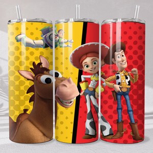 May include: Three cylindrical tumblers with clear lids and straws. The left tumbler features a yellow background with polka dots, Bullseye the horse, and Buzz Lightyear. The right tumbler has a red background with polka dots, Jessie, and Woody.