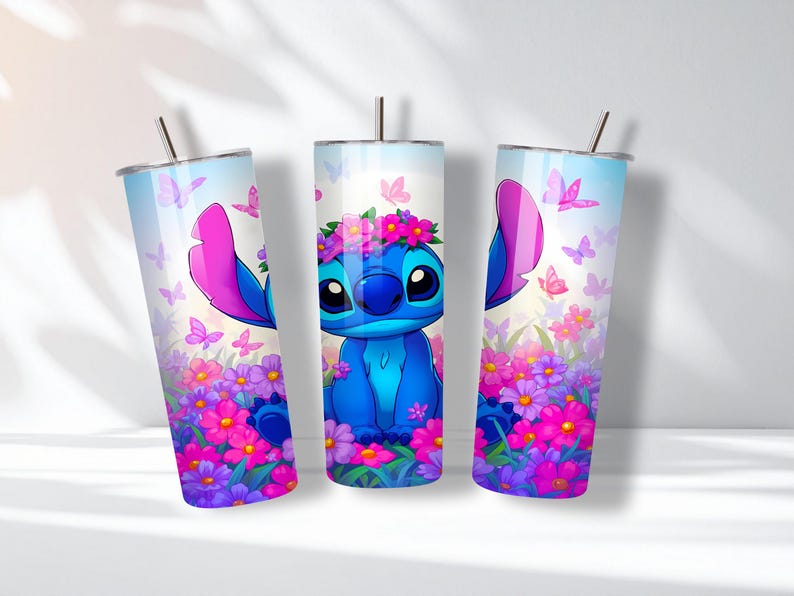 May include: Three cylindrical tumblers featuring a blue alien character with large ears and a flower crown. The design includes a vibrant garden of pink, purple, and blue flowers with scattered butterflies against a light blue sky background.
