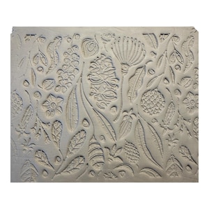 May include: A rectangular, light grey block with a detailed relief pattern of various botanical elements. The design includes stylized flowers, leaves, seed pods, and other natural forms, creating a textured surface. The overall theme is nature and botanical.