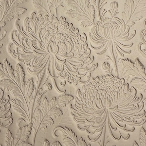 May include: Close-up of a beige floral pattern with embossed chrysanthemum flowers and leaves. The design features detailed, raised relief, creating a textured surface. The repeating pattern is suitable for wallpaper or fabric.
