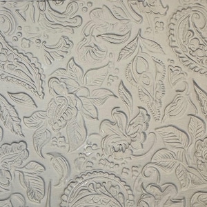 May include: Close-up of a textured, off-white surface with an embossed floral and paisley pattern. The design features detailed leaves, flowers, and teardrop-shaped paisley elements, creating a repeating, ornate design.