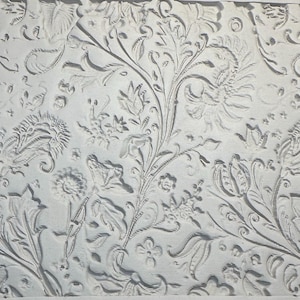 May include: A light grey embossed floral pattern featuring detailed flowers, leaves, and vines. The design includes a variety of flower and foliage shapes, creating a textured, repeating pattern. The overall effect is a classic, elegant design.