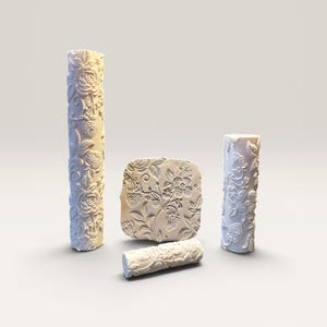 May include: A set of four off-white textured tools for clay or dough, including two tall cylindrical rollers, one short cylindrical roller, and one square-shaped stamp, all featuring embossed patterns of strawberries, leaves, and floral vines.