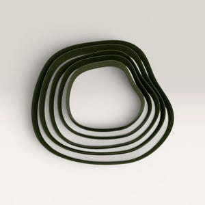 May include: A set of five nested, dark olive green, organic-shaped rings or bands. Each band features a smooth, continuous, and irregular rounded contour, stacked concentrically to create a layered, depth-filled appearance with a matte finish.