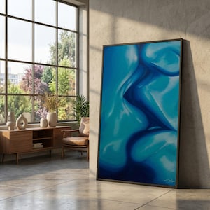 Könnte beinhalten: Ein gerahmter Kunstdruck mit abstrakter Kunst in Blautönen. Das Kunstwerk zeigt eine fließende, geschwungene Form mit verschiedenen Tönen von hell- und dunkelblau. Der Druck wird in einem modernen Innenraum vor einer Betonwand präsentiert.