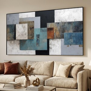 May include: Abstract geometric wall art featuring a black frame. The artwork showcases a collage of rectangular and square shapes in various colors, including white, gray, blue, brown, and black. The textured surface adds depth to the design.
