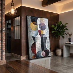 Op de afbeelding: Een groot rechthoekig ingelijst kunstwerk aan de muur met een abstracte compositie van overlappende geometrische vormen, waaronder cirkels en halve cirkels in tinten zwart, grijs, donkerrood, mosterdgeel en wit met een getextureerde afwerking.